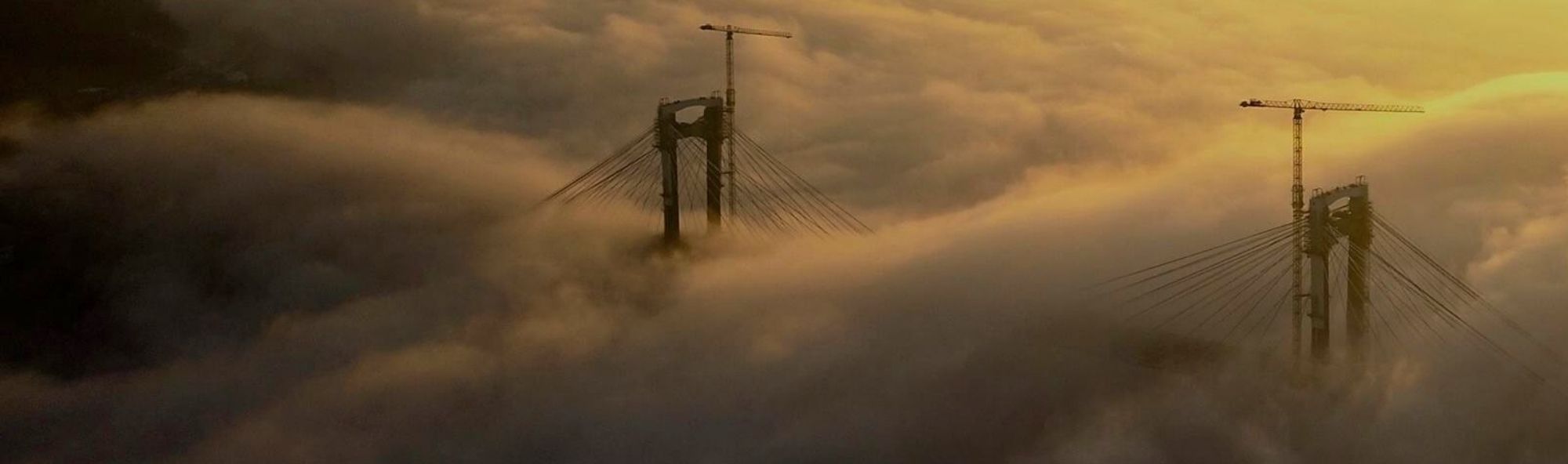 A ponte de Rande en obras na néboa durante o solpor.
